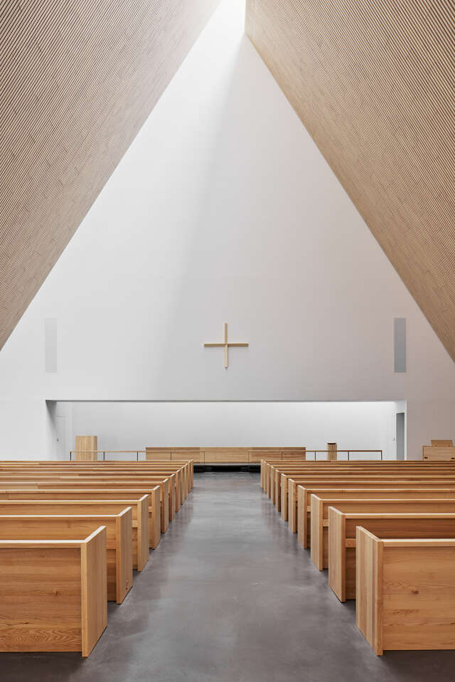 A hallway with pews on both sides leading up to an altar.