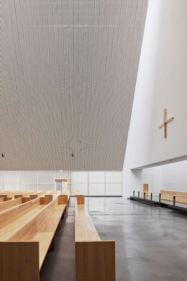 A large room with wooden pews looking at an altar.