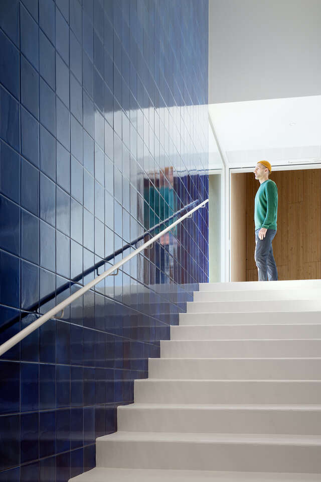 White steps next to a blue tiled wall leading up to a person looking outside.