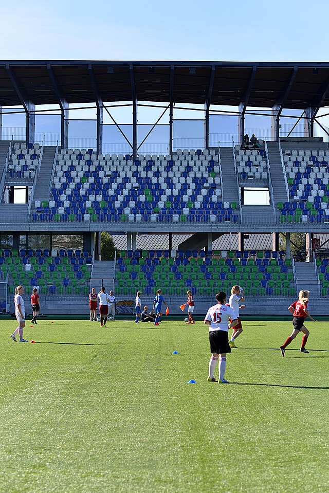 Female football players on the pitch in front of the stands.