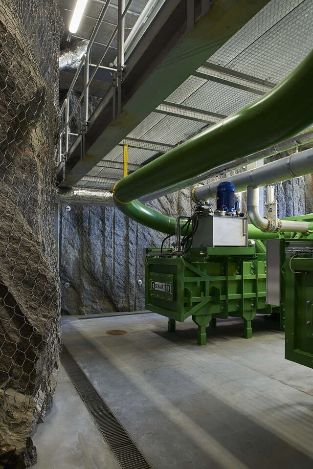 Machinery next to a bare rock wall with a net covering it.
