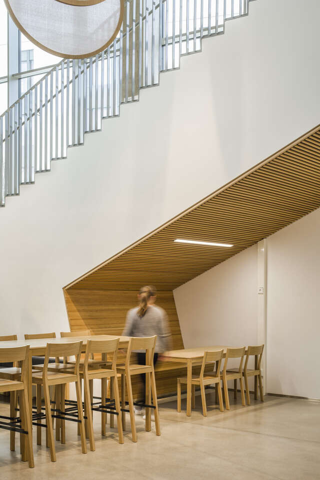 A child nearby a large staircase and walking past a set of tables and chairs
