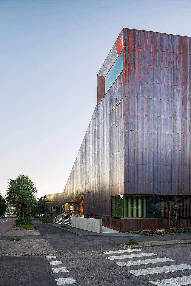 Copper exterior of the chapel reflects red and blue tones during sunset.