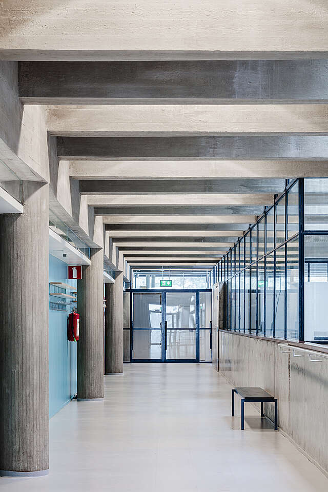 Corridor with concrete and glass elements and. alight blue wall.