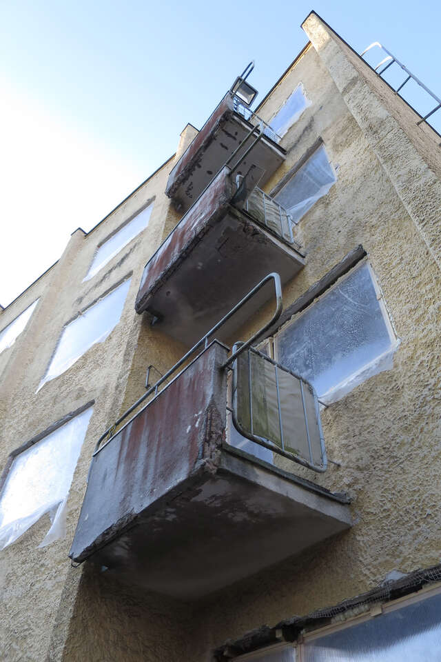 Dirty yellow plastered facade with run down balconies.