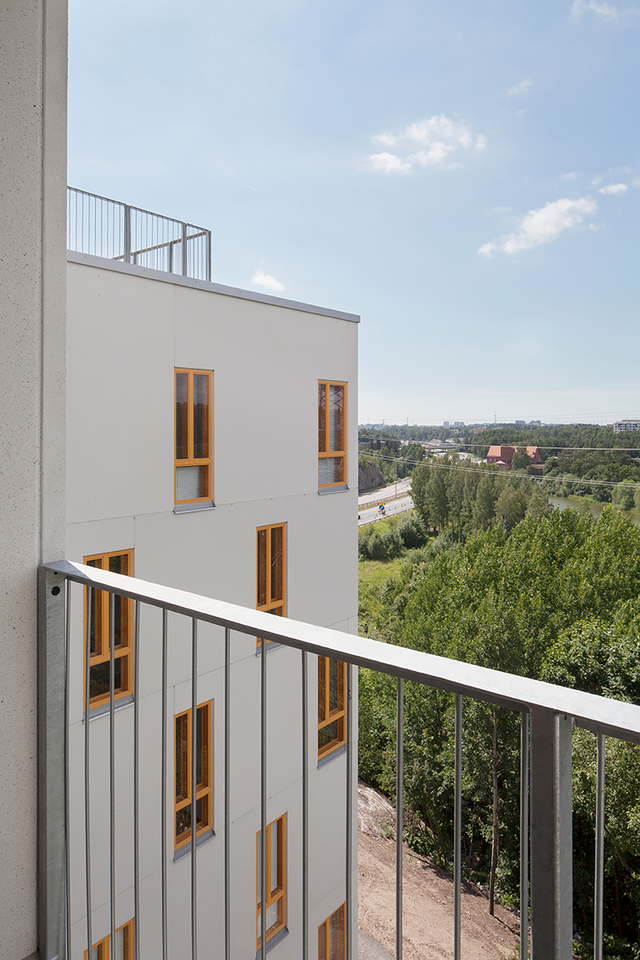 A view from a balcony. You can see white facade and the forest.