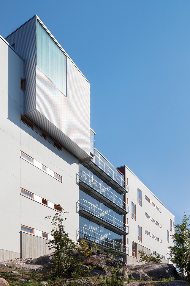 A building, which has white facade and glass wall.