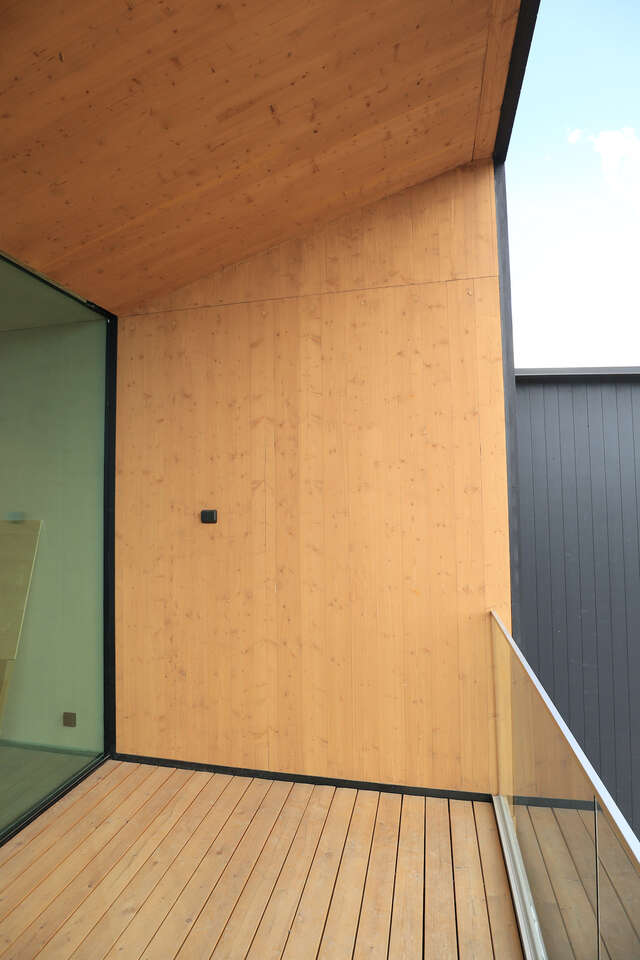 Wooden balcony with glass window on left.