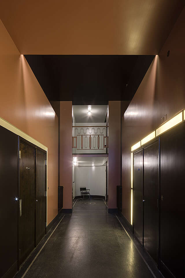 Hallway with black doors and brown walls, the right door is framed by light panels.