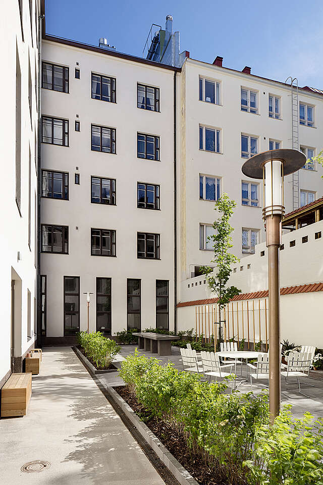 Green courtyard surrounded by white apartment buildings.