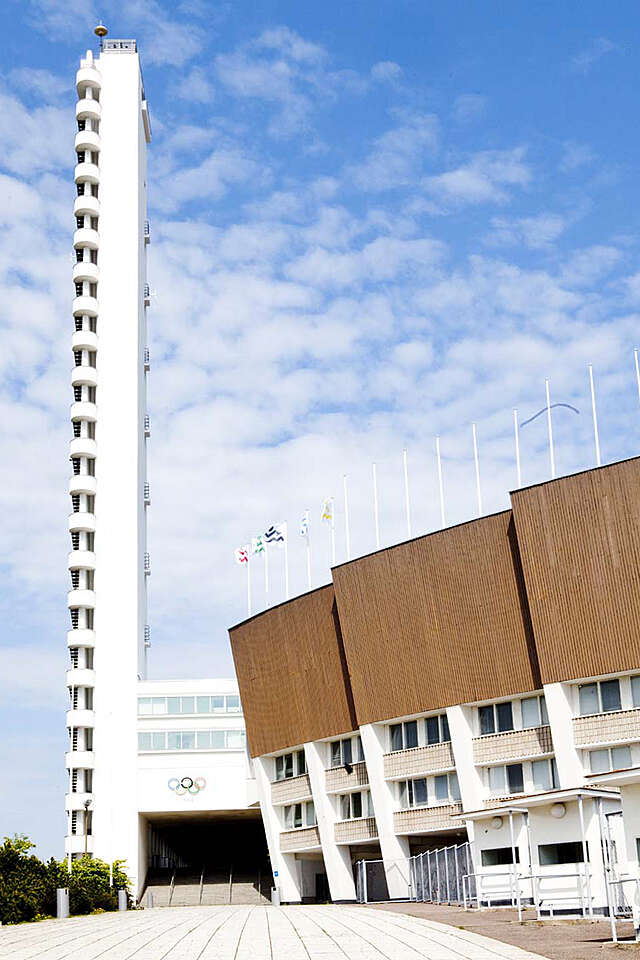 White functionalist tower and wooden-paneled exterior walls with flagpoles on top