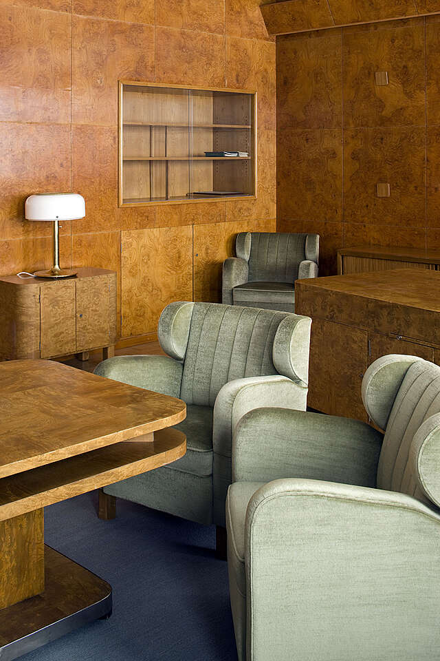 Green velvet armchairs in front of a massive wood table.