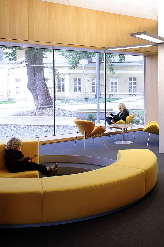 Reading area with yellow sofas and armchairs next to a large window.