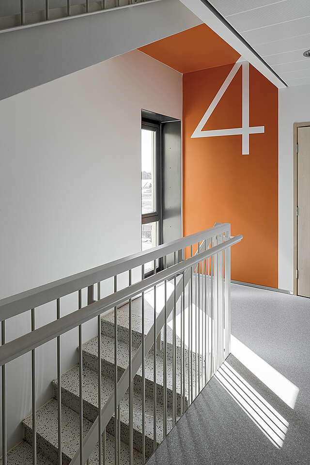 Cold toned stairway with an orange statement color wall displaying the number four.
