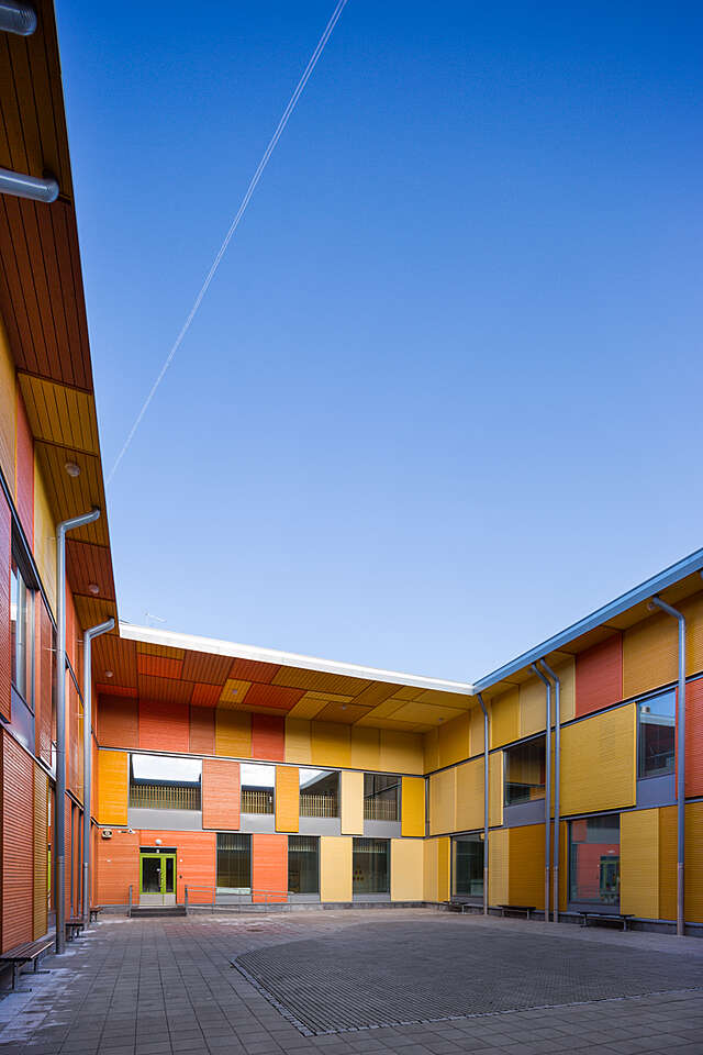 Inner yard surrounded by an orange building with different shade panels.