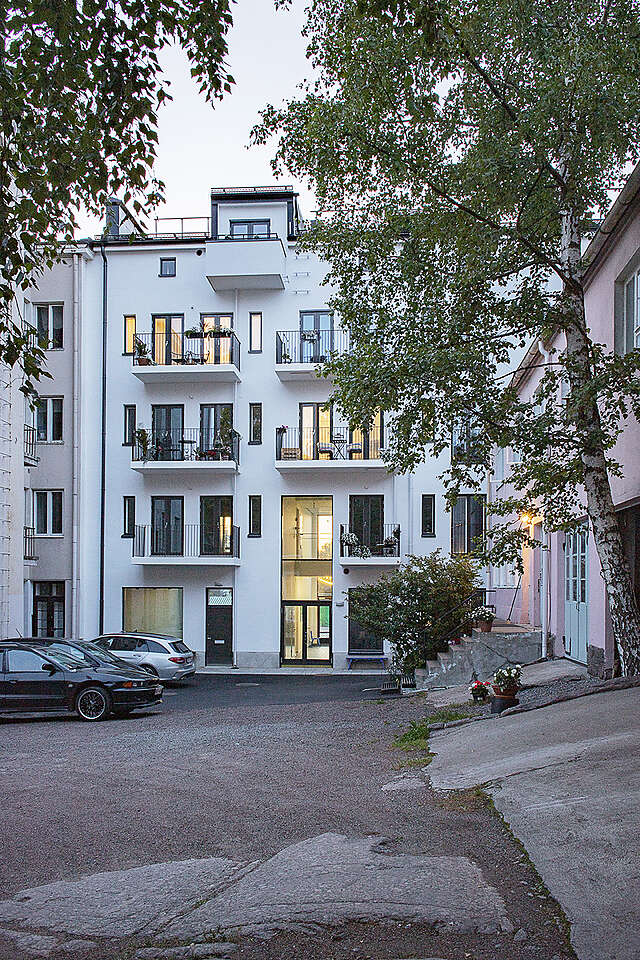 Courtyard in evening light, white facade in the background, lower pink building to the right
