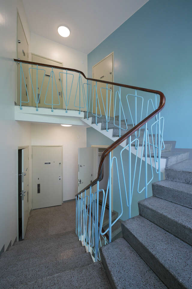 STone staircse with blue metal railing with a triangular pattern.