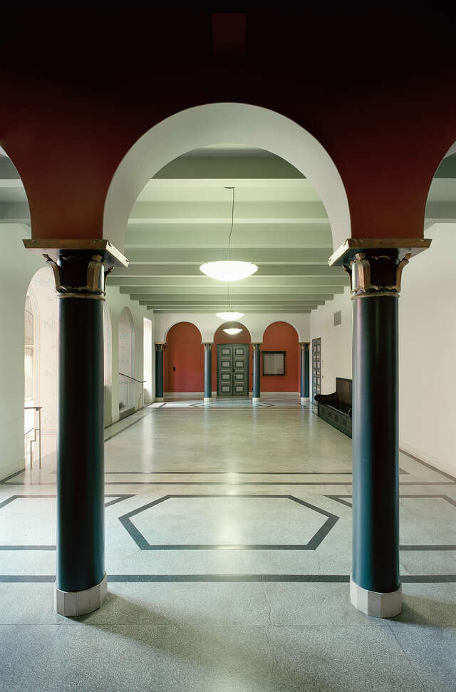 Hallway view through two columns towards arch doors