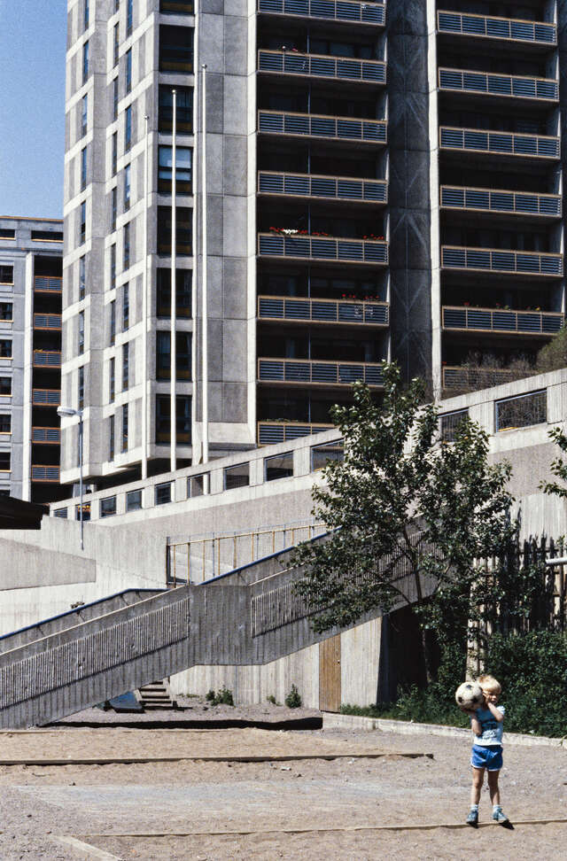 Boy playing with a ball in the high-rise concrete residential area
