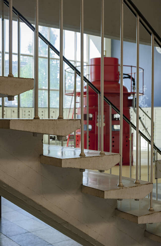 Image of a bright colored piece of machinery captured from behind some thin stair balusters.