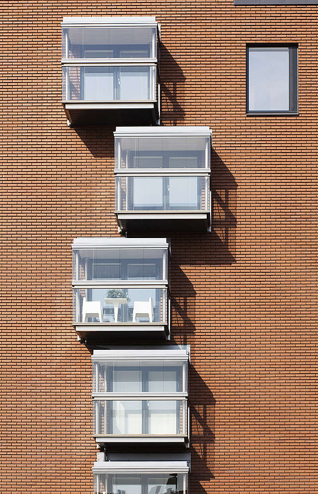 Glazed offset balcony row on a red-brick facade.