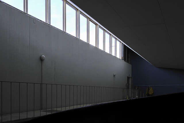 Tumma kuva sisätilasta, jossa pitkä kapea yläikkuna ja tumman sininen taustaseinä.